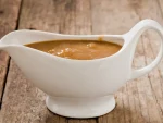 Ham gravy in white gravy boat on wooden table