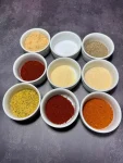 9 small ceramic cups with different spices which make a bbq rub for pulled pork