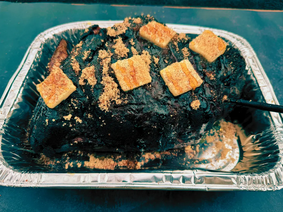 smoked pork butt being wrapped covered in butter, brown sugar, and hot honey