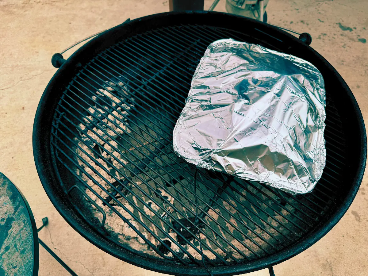 pork butt in foil pan wrapped with foil on the smoker